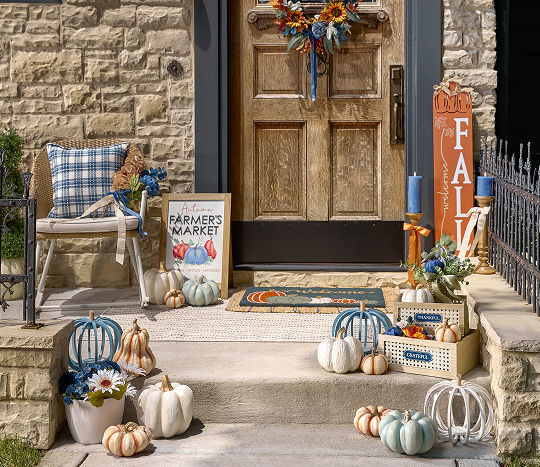A front porch is decorated with fall themed outdoor decor from pOpshelf, including pumpkin-themed accents.