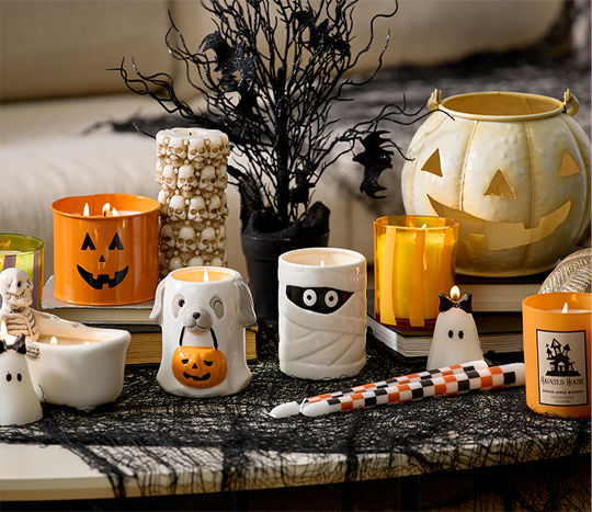 A table features a close-up shot of various Halloween themed candles from pOpshelf including a skeleton in a bath tub, a small ghost wearing a bow, a dog sheet ghost holding a trick-or-treat pumpkin, and other fun Halloween aesthetic candles.
