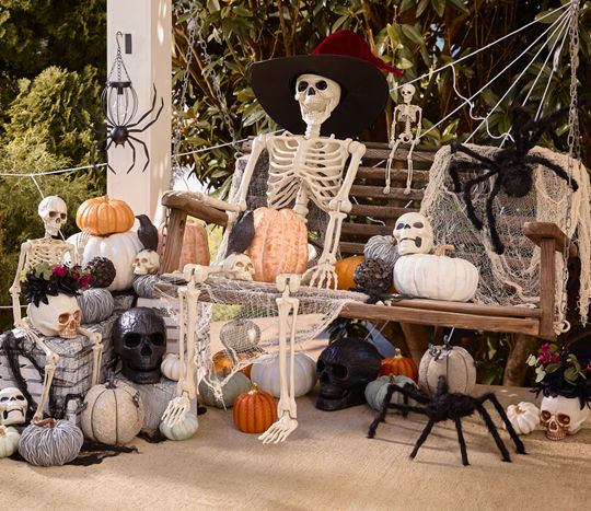 Front porch decorated with skeletons, spiders, pumpkins, skulls & more.