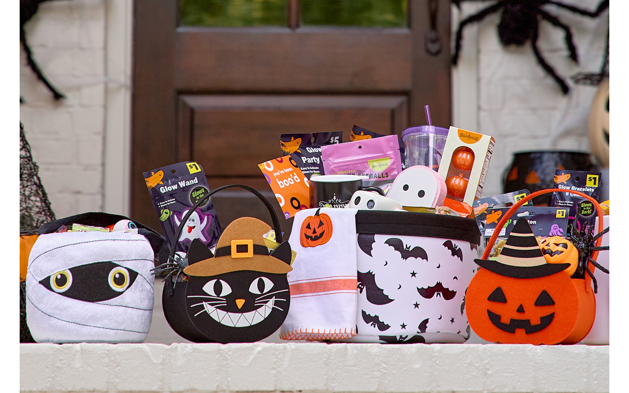 Halloween trick-or-treat buckets and bags filled with candy and goodies on a front porch decorated for Halloween. 