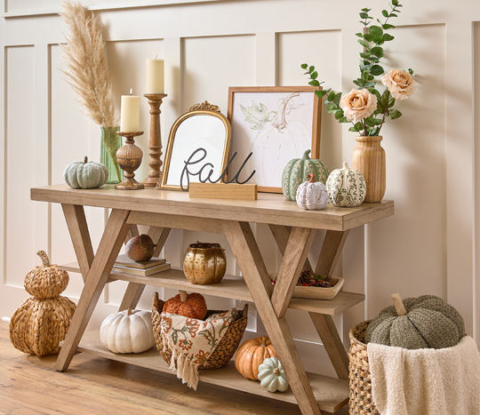 Fall decor, pumpkins, mirror, candleholders, floral, and art on a console table with baskets of fall throws & fall pillows.