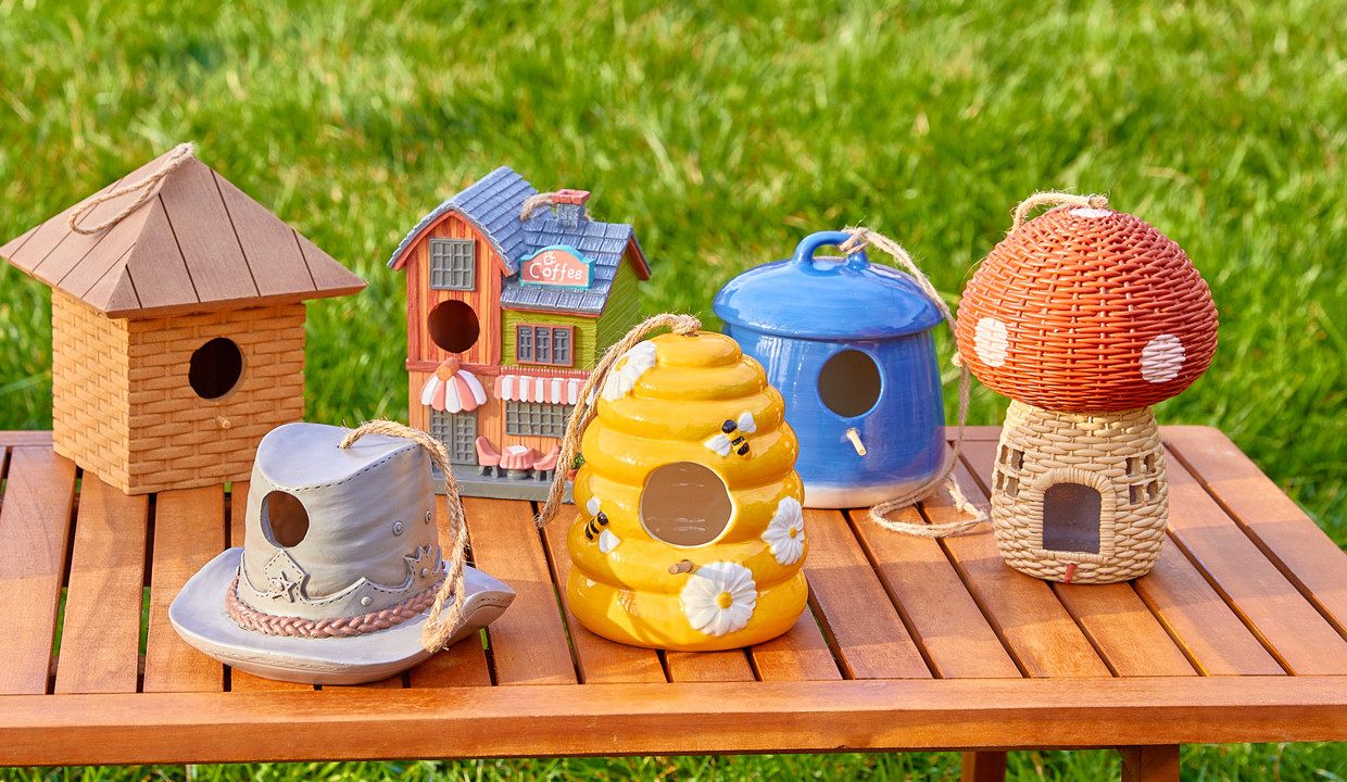Row of birdhouses in various shapes & designs: cowboy hat, bee hive, mushroom, coffee shop, and more.
