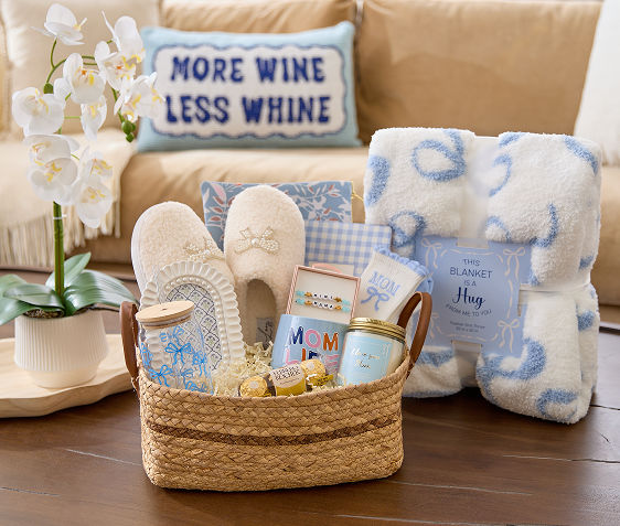 Mother's Day gift basket filled with blue bow-themed gifts: candles, slippers, mugs & more.