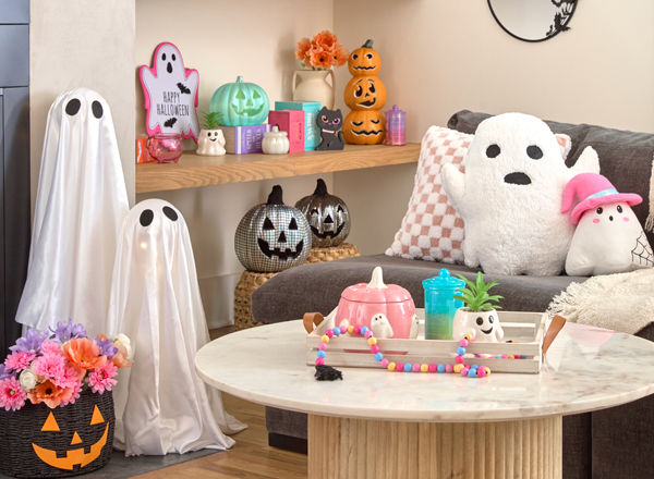 Living room decorated for cute, pastel Halloween decor: sparkly ghost and pumpkins, ghost pillows, pastel pumpkins, ghosts, and Halloween decor.