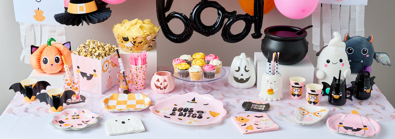 Halloween party table set with party supplies in pastel colors with black accents, a 'boo' balloon & pastel balloon arch, ghost streamers, ghost plates and napkins, and more.