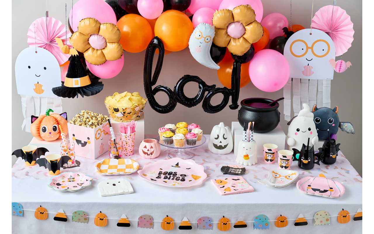 Halloween party table set with party supplies in pastel colors with black accents, a 'boo' balloon & pastel balloon arch, ghost streamers, ghost plates and napkins, and more.