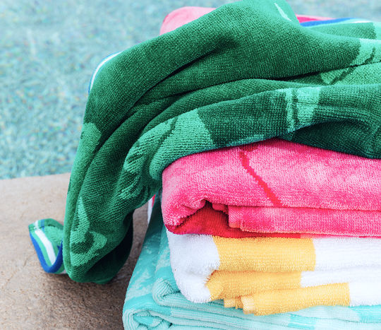Soft multi-colored pool towels hanging poolside.