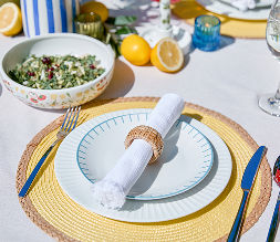 A place setting dish set with touches of yellow and blue set on an outdoor dining table.