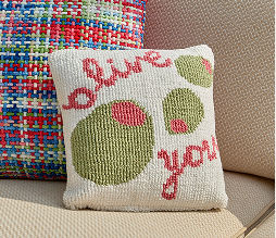 A throw pillow decorated with olives that says, “Olive You”.
