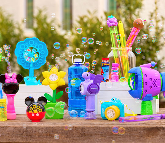 Outdoor table with bubbles, bubble blowers, bubble wands, and bubble machines in various colors and designs.