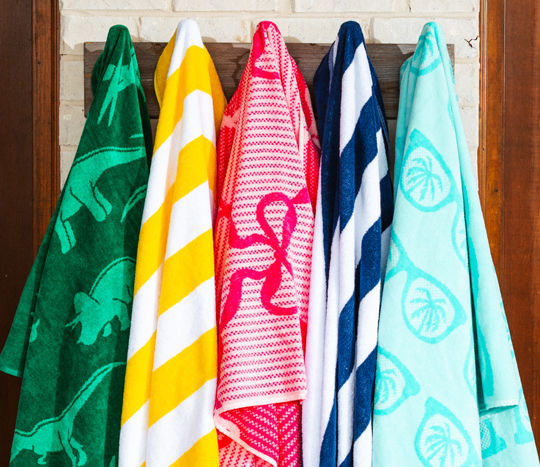 Colorful pool towels hanging from hooks in various patterns and prints