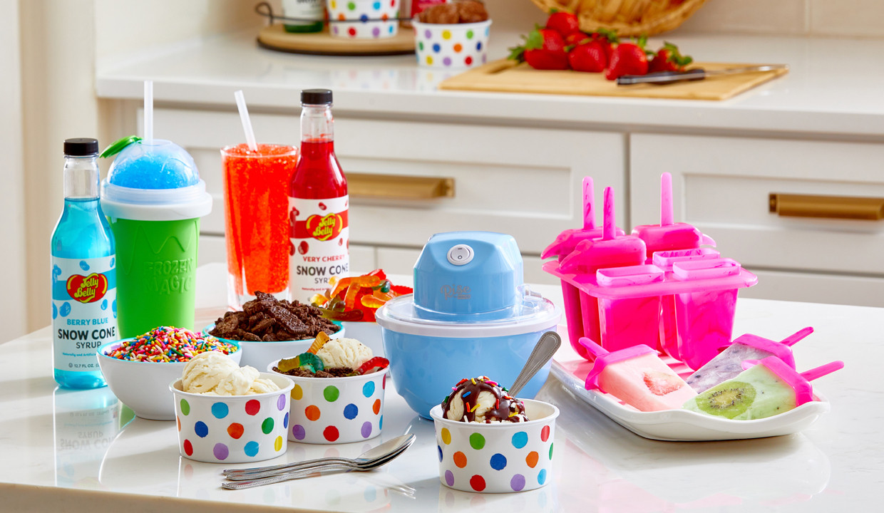 Rise ice cream maker, popsicle molds, and slushy makers on kitchen counter with Jelly Belly syrups, and melamine polka-dot ice cream bowls and tray.