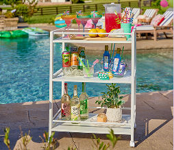 A bar cart featured poolside with different summer drinks displayed with lemon summer decor.