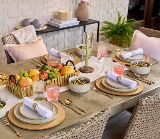 Outdoor dining table set with coastal decor, place settings, trays, candles and more.