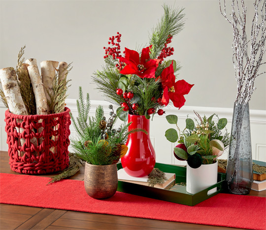 Four vases filled with faux Christmas florals and greenery: red & white poinsettias, frosted & flocked pine and pinecones, Christmas wreath, holly and berries, and more.