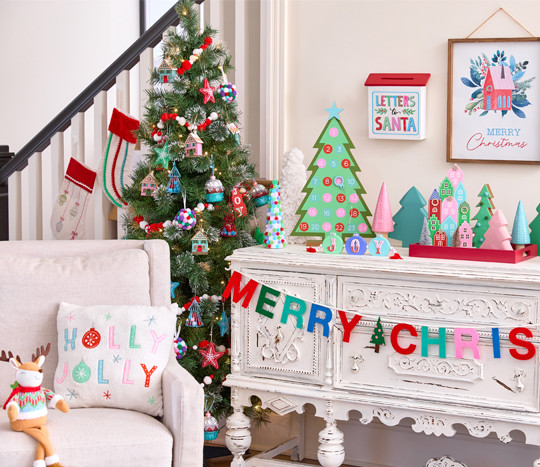 Tree decorated with folklore ornaments in foyer with folklore Christmas decor and pillow and stuffed deer on chair..