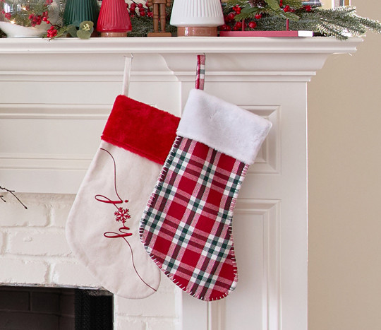 Red plaid and white 'Joy" stockings on a fireplace mantel.