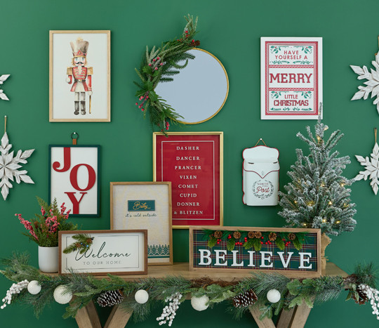 Christmas signs and wall decor in various sizes and designs on a green wall.