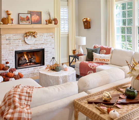 Living room decorated for fall with pumpkin decor, fall pillows and throws, fall candles, fall wall signs, and fall floral.