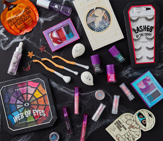 Halloween-themed makeup, nail art, makeup brushes, and false eyelashes on a black background.