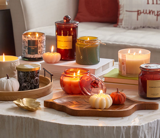 Various fall jar candles and pumpkin-shaped candles in fall scents.