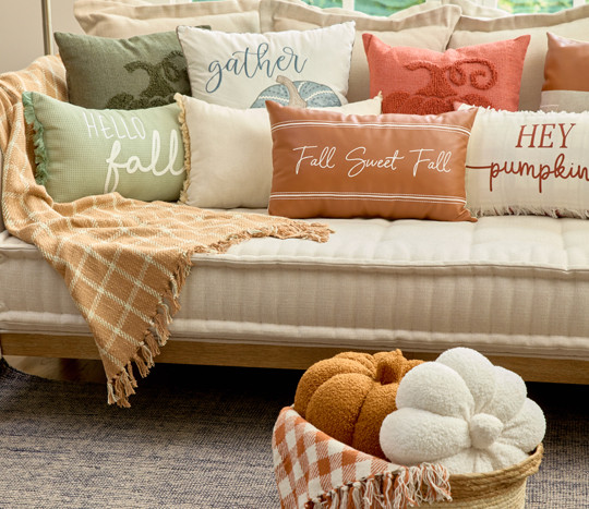 Fall pillows in various colors and designs on a living room sofa.