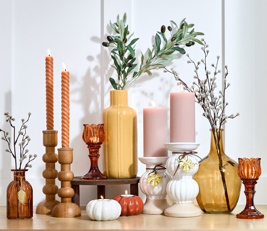 Fall vases and candleholders in various designs and colors on an entryway table.