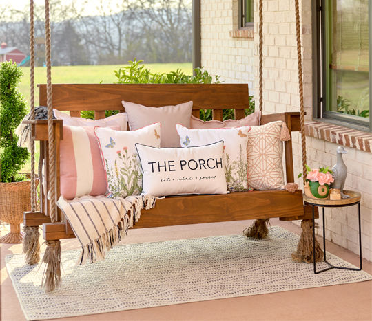 Porch swing with multiple outdoor pillows in various sizes, colors, and designs from pOpshelf.
