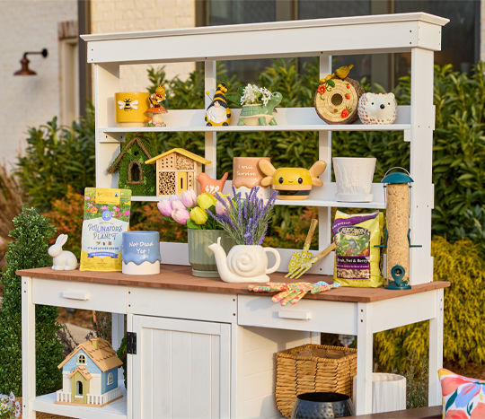 Colorful planter & pots, birdhouses, and outdoor decor on a white potting bench with shelves.