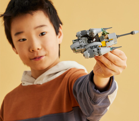 Young boy playing with a Star Wars LEGO toy. Save on LEGO sets at pOpshelf.