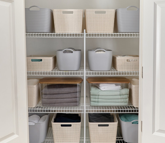 Plastic storage baskets in wheat and gray, and clear plastic storage bins with wooden lids solve clutter in your pantry.