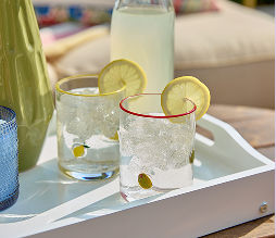 Cute decorative glassware filled with lemonade sitting on a white serving tray.