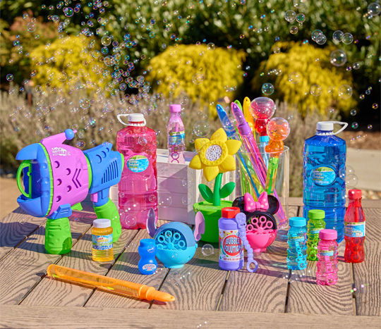 Outdoor table with bubbles, bubble blowers, bubble wands, and bubble machines in various colors and designs.