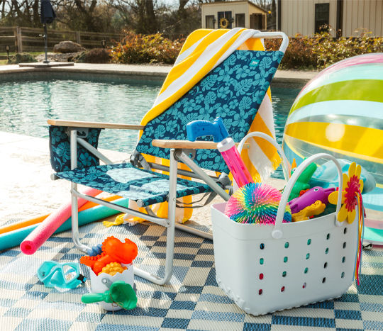 Beach chair next to pool with towels, pool floats, bag, toys and more.