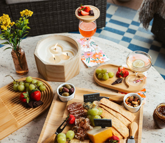 Various charcuterie boards set with cheese, crackers, candles, drinks, and more.