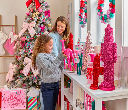 Mother and daughter decorating room with the Merry Merry decor collection from pOpshelf: tree ornaments, bows, wall art, tinsel nutcrackers, bottlebrush trees, candles, ornament wreaths & garland.