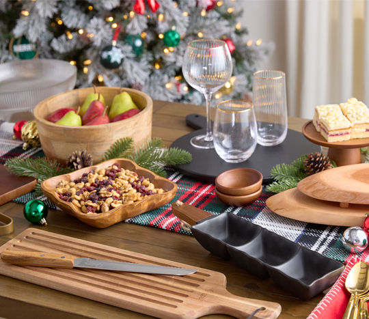 Holiday buffet set with wooden charcuterie boards, serving trays & bowls, and gold-rimmed wine glasses from pOpshelf.