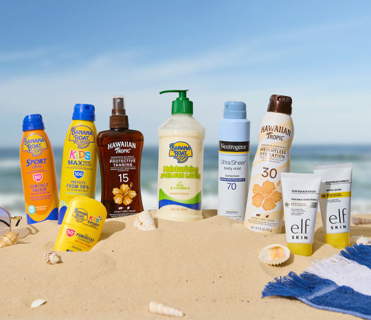 Various brands of sunscreen sitting in sand at beach