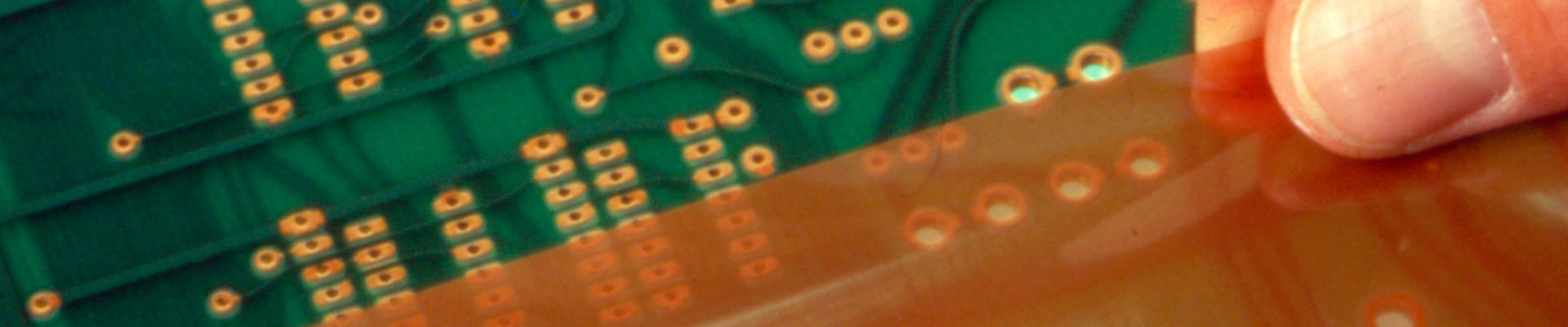Man's fingers apply pressure-sensitive-adhesive protective film to an electronic circuit board. 