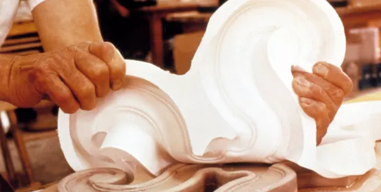 Man's hands remove Silastic silicone moldmaking rubber "negative" mold from an ornate piece of original woodwork