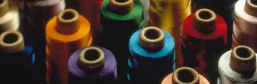Various colored threads on large spools. Textiles industry. Textile additives Textiles finishes