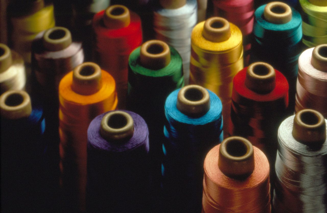 Various colored threads on large spools. Textiles industry. Textile additives Textiles finishes