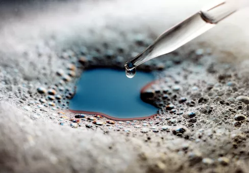 Glass eyedropper dispenses silicone antifoam into foam-covered liquid