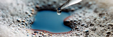 Glass eyedropper dispenses silicone antifoam into foam-covered liquid.