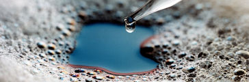 Glass eyedropper dispenses silicone antifoam into foam-covered liquid.
