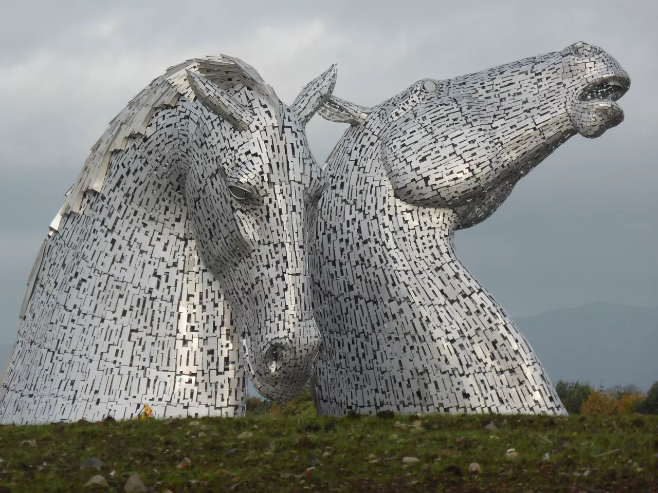 Image of the kelpies from a distance against a cloudy sky.