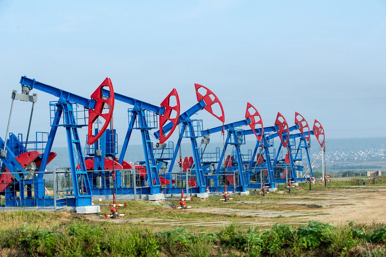 A row of oil pump jacks working in an oil field