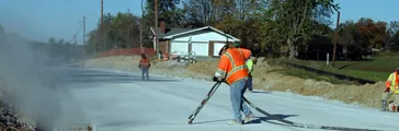 Man in safety orange, airblasting concrete pavement joints.