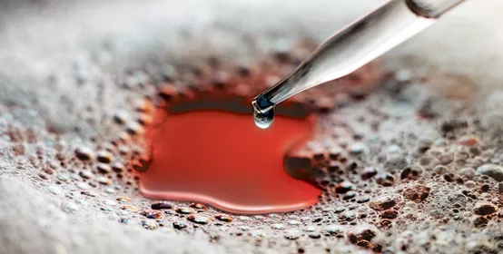 Glass eyedropper dispenses silicone antifoam into a foam covered liquid. The liquid is red. Reference AV03988 Edited by AGP For use on Dow Corning 102F additives website. "Power up your coatings with effective foam control."