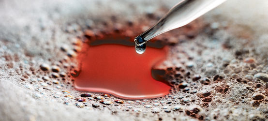 玻璃滴管将硅酮消泡剂分配到泡沫覆盖的红色液体中